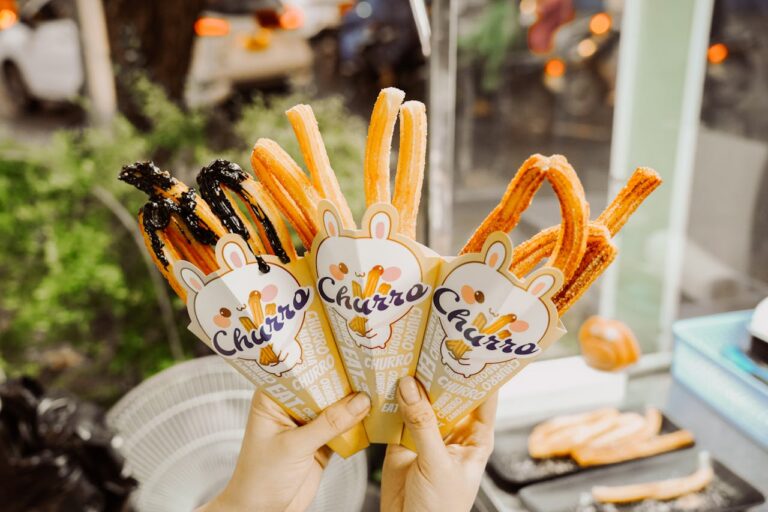 Close-up of gourmet churros in cones being held outdoors. Perfect sweet street snack.