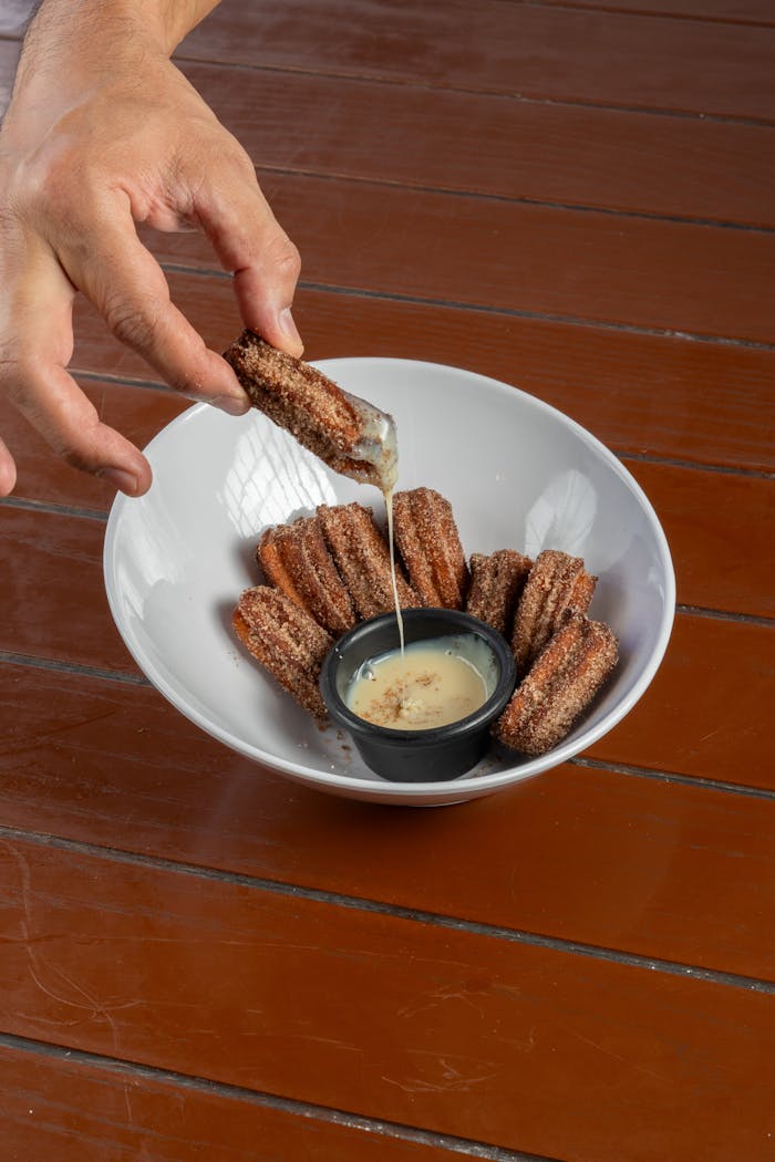 A close-up of churros with cinnamon sugar, ready to be enjoyed with dipping sauce. Perfect for dessert lovers.