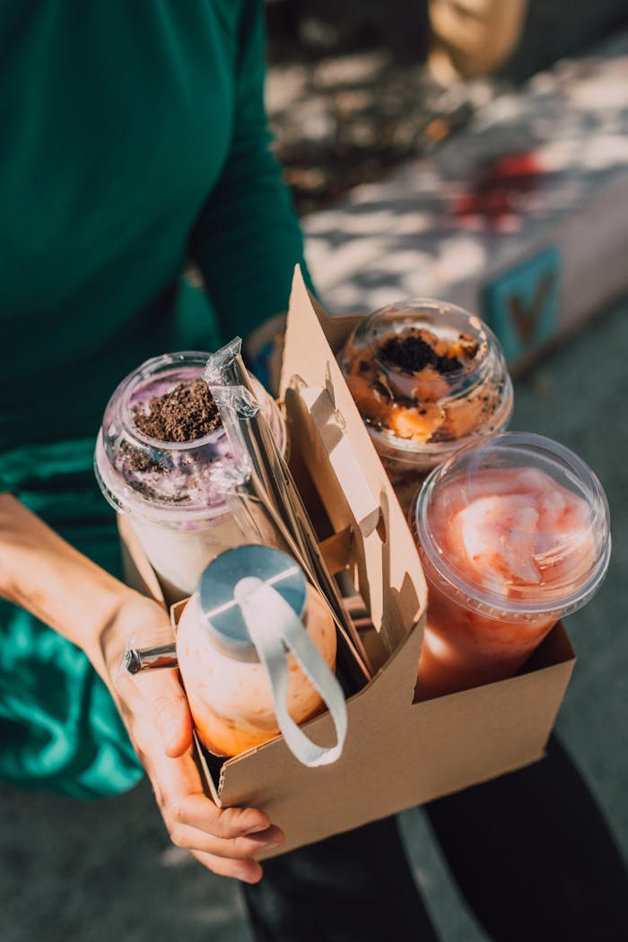 A variety of colorful takeaway drinks in a cardboard holder under sunlight, capturing a vibrant summer vibe.